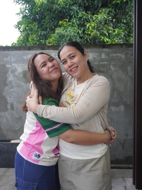 Two women hugging and smiling outdoors