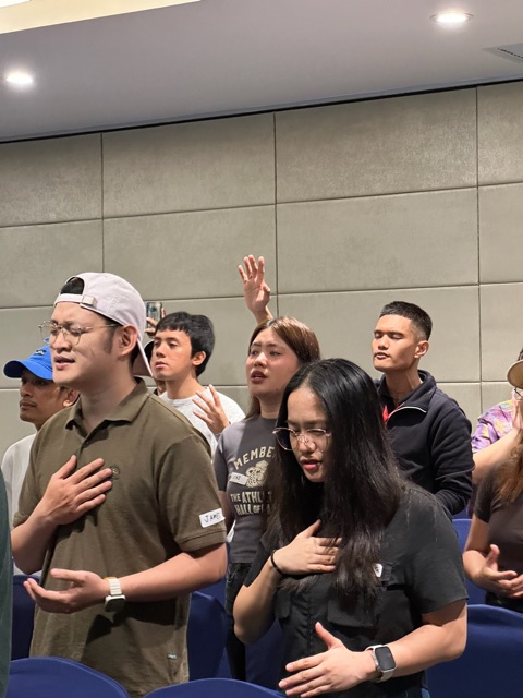 Young adults standing in worship with hands on their hearts
